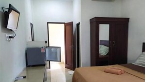 Een hotelkamer met een bed, een kledingkast, een bureau met een computer en een televisie.