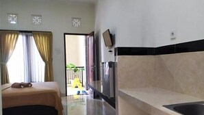 Hotelkamer met een bed, een klein keukenhoekje, een aan de muur bevestigde televisie en uitzicht op het balkon.