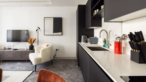 Een moderne keuken met een vast kookeiland, een flatscreen televisie en een zithoek met een bank en stoelen.