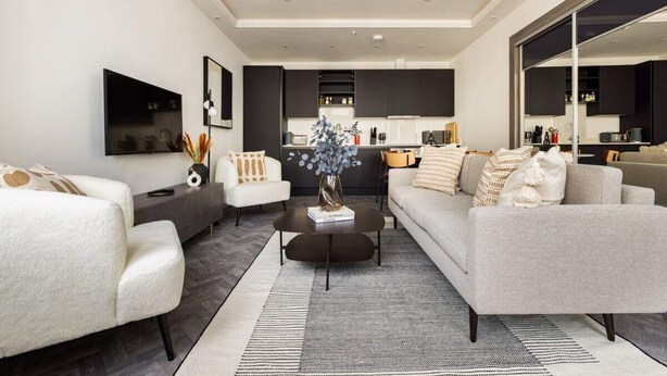 Een moderne woonkamer met een bank, fauteuils, een salontafel en een televisie.
