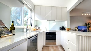 Cuina moderna amb armaris blancs, forn integrat i rentapesos.
