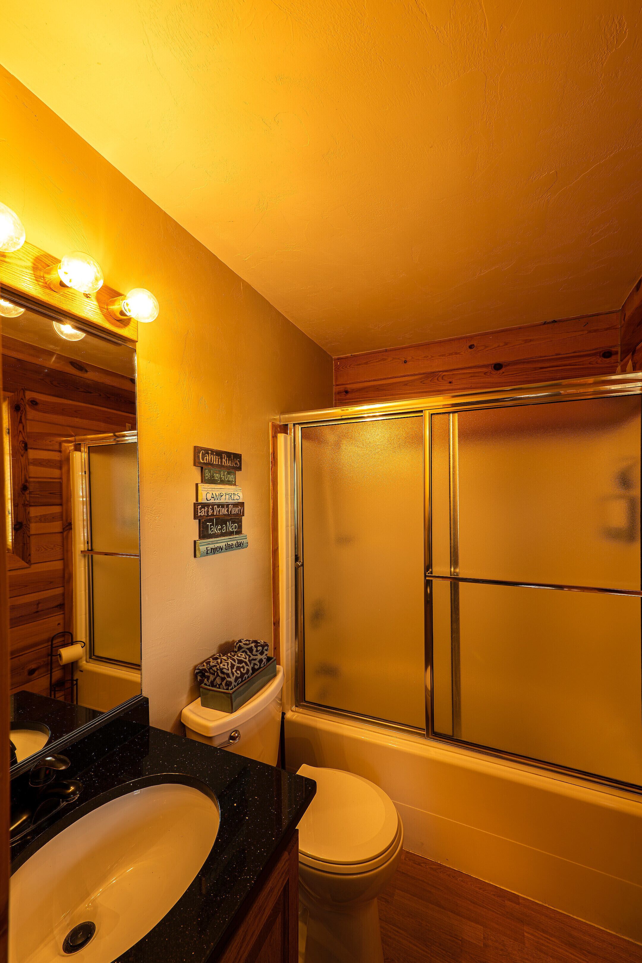 A bathroom with a wooden vanity, a toilet, and a shower enclosure.