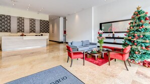 A modern lobby with a reception desk, seating area, and a Christmas tree.