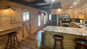 A wooden cabin-style kitchen with a granite countertop, wooden cabinets, and a refrigerator. - NEW! Western Cabin, Super Fast Free WiFi, NFL Sunday, Arcade, Fishing & 2 Pools! (Sevierville)