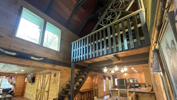 A rustic cabin interior with a wooden staircase, a dining area, and a kitchen. - NEW! Western Cabin, Super Fast Free WiFi, NFL Sunday, Arcade, Fishing & 2 Pools! (Sevierville)