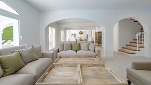 Un salon spacieux avec un grand canapé, une table basse en bois et un escalier menant à un niveau supérieur.