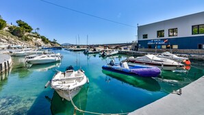 Un port de plaisance avec des bateaux amarrés, un bâtiment portant l’inscription « ÉCOLE DE PLONGÉE LES BASÉTES – ESCUELA DE BUCEO », et une eau d’un bleu limpide.