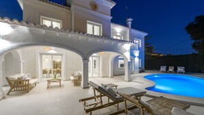 Une maison moderne dotée d’une piscine, d’un espace salon extérieur et d’une terrasse bien éclairée.