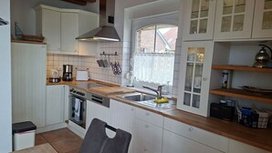 A kitchen with white cabinets, a wooden countertop, a stove, a sink, and a window with a view. - View of the lake - vacation home with a fantastic view (Sternberg)