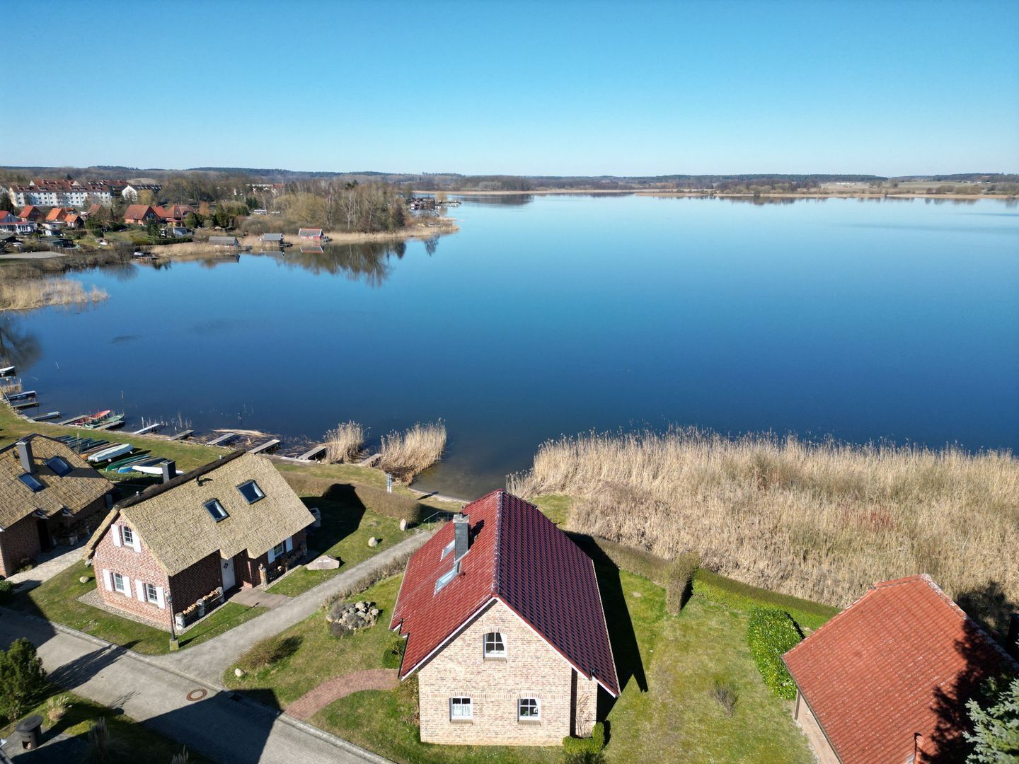 A lakeside village with traditional houses, a clear sky, and calm water.