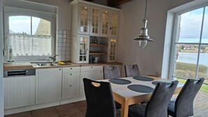 A kitchen with a dining area, a large window, and a view of a body of water. - View of the lake - vacation home with a fantastic view (Sternberg)