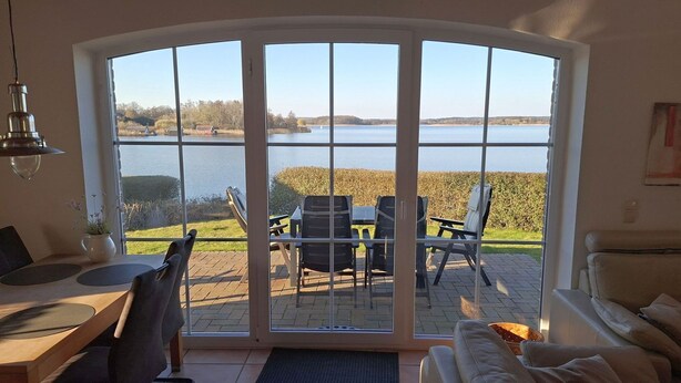 A room with a large sliding glass door leading to an outdoor patio with a table and chairs. - View of the lake - vacation home with a fantastic view (Sternberg)
