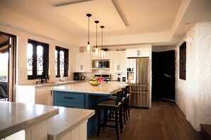 A modern kitchen with a central island, stainless steel appliances, and pendant lighting.