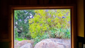 A window with a view of a garden featuring rocks and various plants. - PCH Bunkhouse (San Luis Obispo)