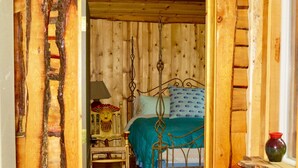 A rustic wooden room with a bed, a chair, and a small table. - PCH Bunkhouse (San Luis Obispo)