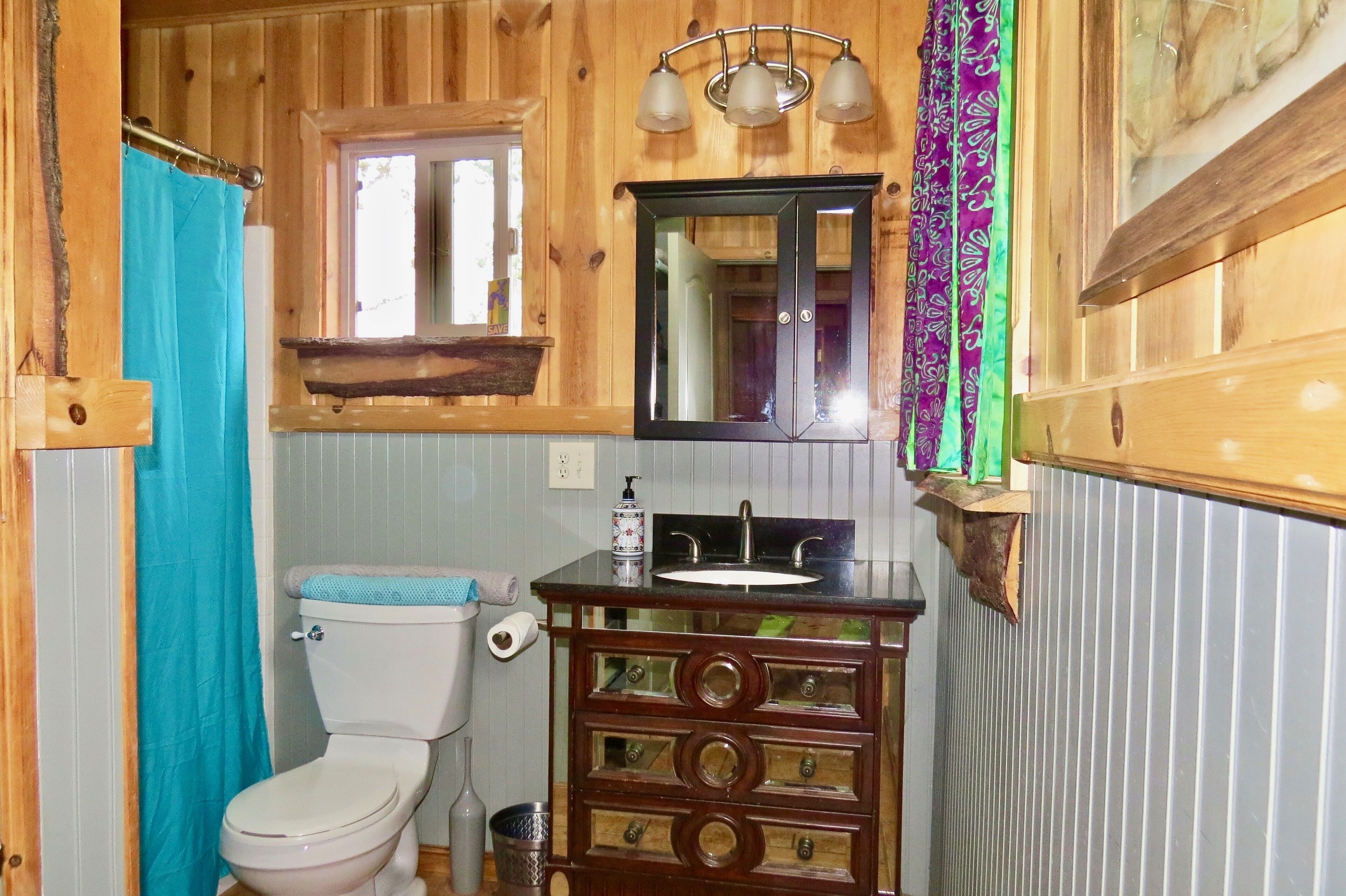A wooden bathroom with a toilet, sink, and mirror.