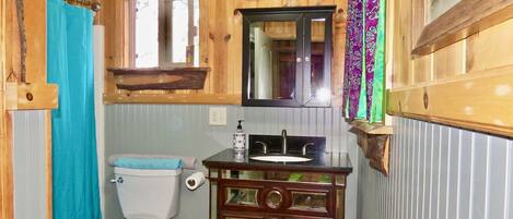 A wooden bathroom with a toilet, sink, and mirror.