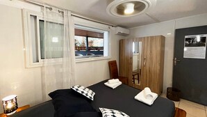 A bedroom with a bed, a window with curtains, a wardrobe, and a bedside lamp.