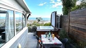 A patio with a table and chairs, a hot tub, and a view of the city.