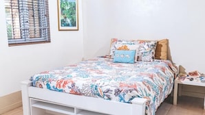 A bedroom with a bed, a nightstand, and a window with blinds.
