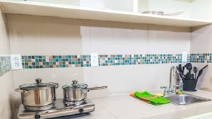 A kitchen with a stove, pots, a sink, and a tiled backsplash.