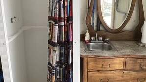 Ein Badezimmer mit einer Duschvorhang aus Büchern, einem hölzernen Waschtisch mit Spiegel und einem Waschbecken.