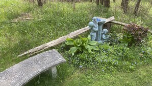 Eine Steinsitzbank mit aufwendigen Schnitzereien, umgeben von üppiger Vegetation und einer Zierbrunnen.