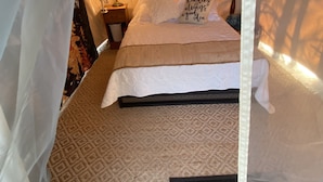 Ein Schlafzimmer mit Himmelbett, gemustertem Teppich und einer Nachttischlampe.