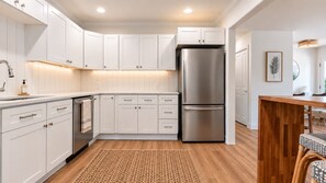 Una cocina moderna con armarios blancos, electrodomésticos de acero inoxidable y una mesa de comedor de madera.