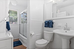 A modern bathroom with a shower, toilet, sink, and a window with blinds. - Spacious 2 bedroom just a 2 min walk to the beach! Pet Friendly. Pool (Myrtle Beach)