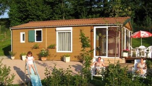Et træhus med terrasse, en lille pool og udendørs møbler.