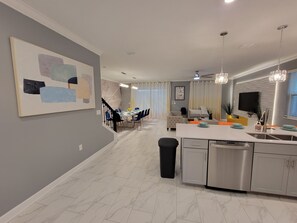 Enjoy meals in the spacious kitchen and dining area, featuring a long table and comfortable seating.