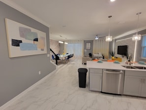 Enjoy meals in the spacious kitchen and dining area, featuring a long table and comfortable seating.
