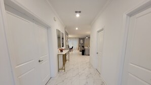 A hallway with white doors, a marble floor, and a dining area with a table and chairs. - Disney theme park 10 mmins/Storey Lake 9 Beds /Lake View Single House (kissimmee)