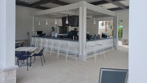 An outdoor bar area with white bar stools, a counter, and ceiling fans. - Disney theme park 10 mmins/Storey Lake 9 Beds /Lake View Single House (kissimmee)