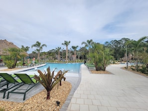 Relax by the resort's clear blue pool surrounded by lush greenery and comfortable lounge chairs.