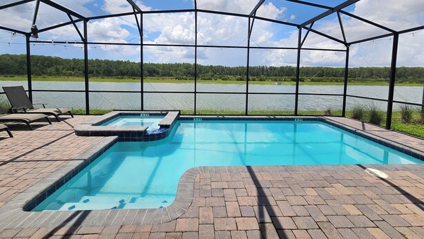 A covered outdoor swimming pool with a view of a lake and trees. - Disney theme park 10 mmins/Storey Lake 9 Beds /Lake View Single House (kissimmee)