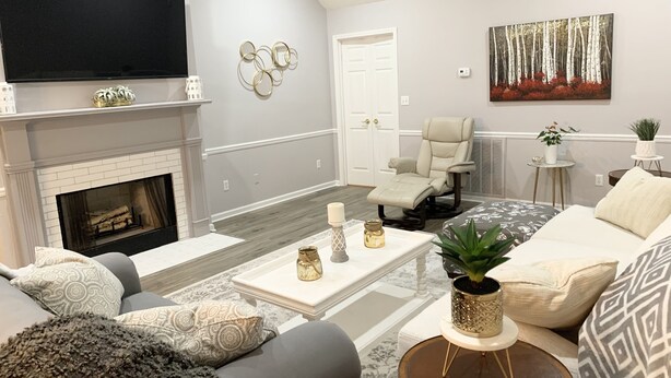 Un salon moderne avec une cheminée, un fauteuil inclinable, un canapé et un téléviseur à écran plat.