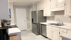 Une cuisine moderne avec des meubles blancs, des appareils en acier inoxydable et un plan de travail en bois.