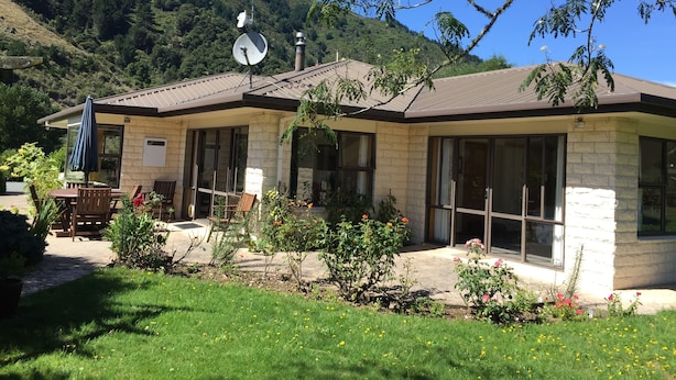 Uma casa com fachada de pedra, janelas amplas e antena parabólica.