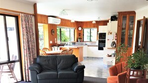 Uma sala de estar com sofá, mesa de centro de madeira e um canto de jantar com cadeiras e mesa.