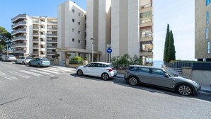 Een modern gebouw met meerdere verdiepingen, een opvallende ingang en een parkeerplaats met auto's.
