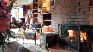 A cozy living room with a fireplace, a bookshelf, and a comfortable chair.