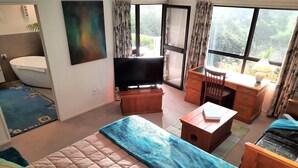A hotel room with a bed, a desk, a chair, a television, and a bathroom.