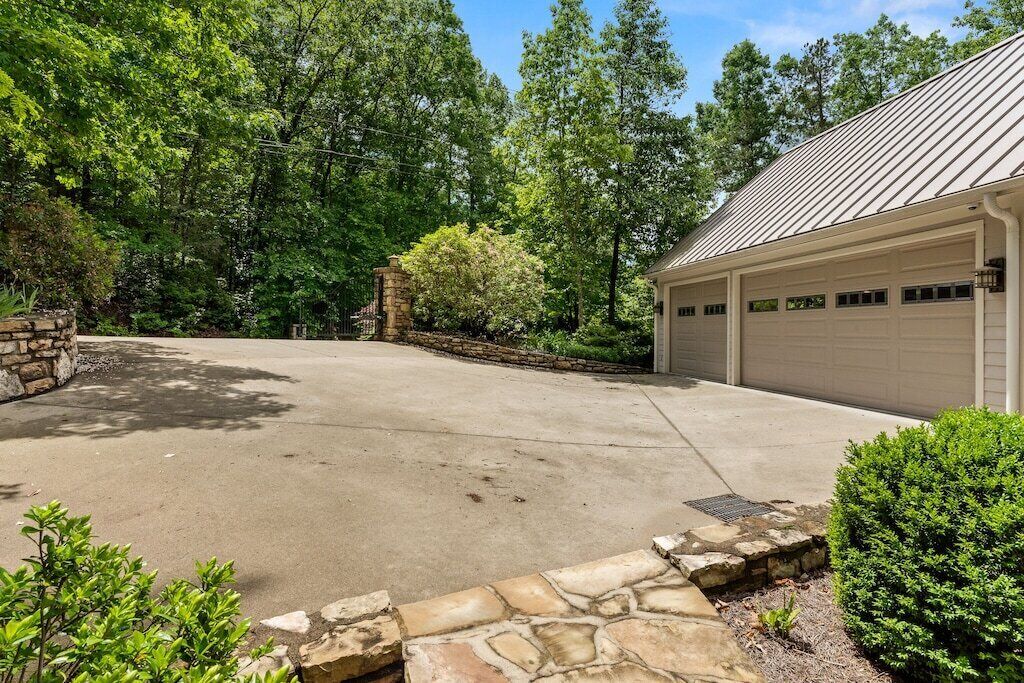 A garage with a metal roof, surrounded by a stone wall and greenery.