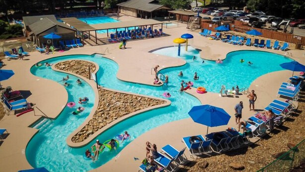 A swimming pool with multiple lanes and a separate shallow area, surrounded by lounge chairs and umbrellas. - Large Luxury Home w/Hot Tub & Game Room with access to Rumbling Bald Resort (Lake Lure)