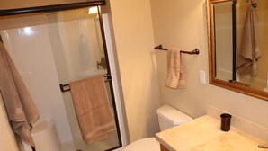 A bathroom with a glass-enclosed shower, a toilet, a sink, and a mirror. - Easy freeway access, 1.5 miles to Hayward Field (Eugene)