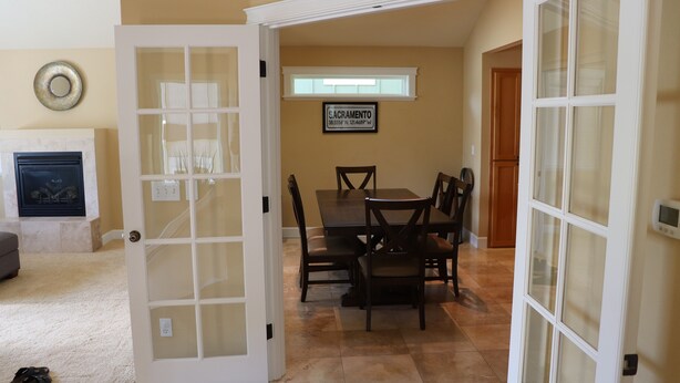 A dining area with a table and chairs, a fireplace, and a door leading to another room. - Easy freeway access, 1.5 miles to Hayward Field (Eugene)