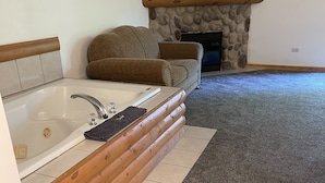 A bathroom with a bathtub, a wooden bench, and a stone fireplace. - Newer Rustic WiFi Villa by Starved Rock sleeps 7. A guest favorite!! (Utica)