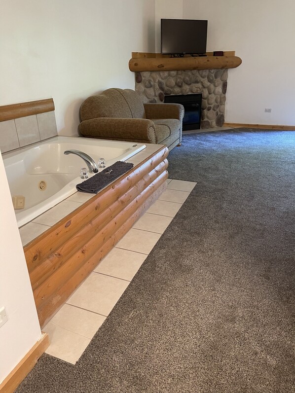 A bathroom with a bathtub, a wooden bench, and a stone fireplace. - Newer Rustic WiFi Villa by Starved Rock sleeps 7. A guest favorite!! (Utica)